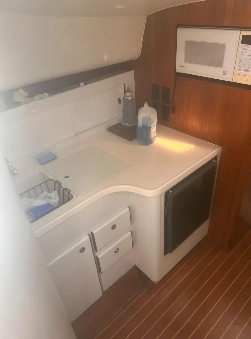 Slide: The Image of 1995 Tiara Yachts 2900 Open interior kitchen with microwave and wooden flooring. - 26