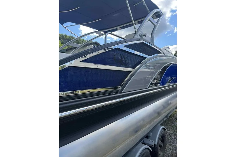Slide: The Image of 2025 Bennington 25QXSBWA pontoon boat with sleek design and blue accents. - 16