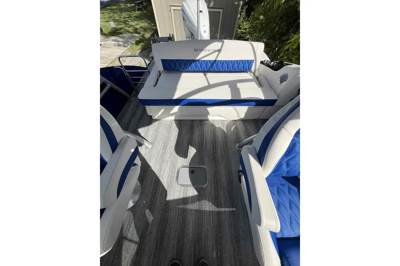 Slide: The Image of 2025 Bennington 25QXSBWA boat interior with blue and white seating and gray flooring. - 22
