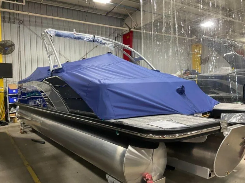 Slide: The Image of 2025 Bennington 25QXSBWA pontoon boat with blue cover in a storage facility. - 3