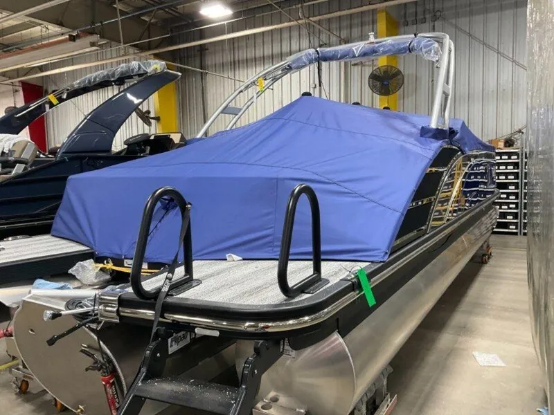 Slide: The Image of 2025 Bennington 25QXSBWA pontoon boat with blue cover in a warehouse. - 4