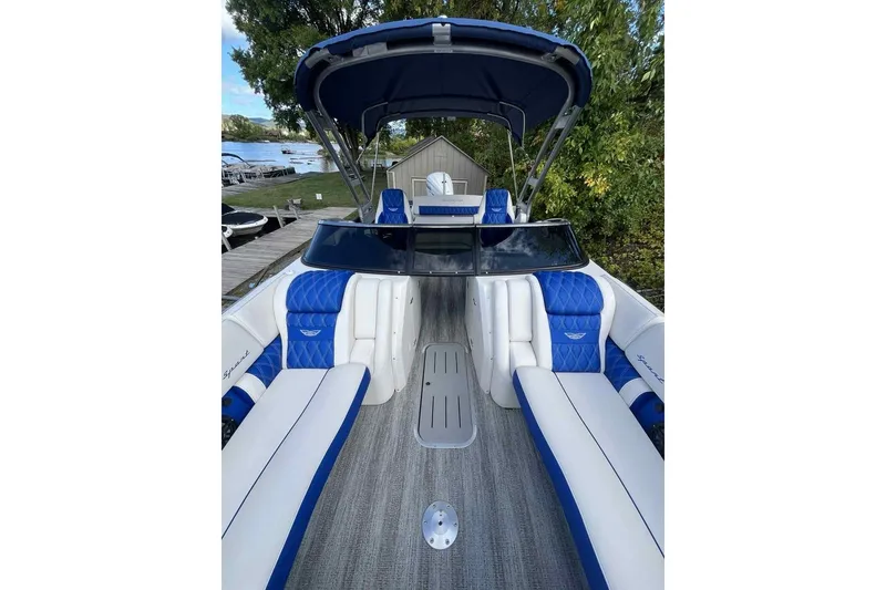 Slide: The Image of 2025 Bennington 25QXSBWA boat with blue and white seating, docked near a lake. - 9