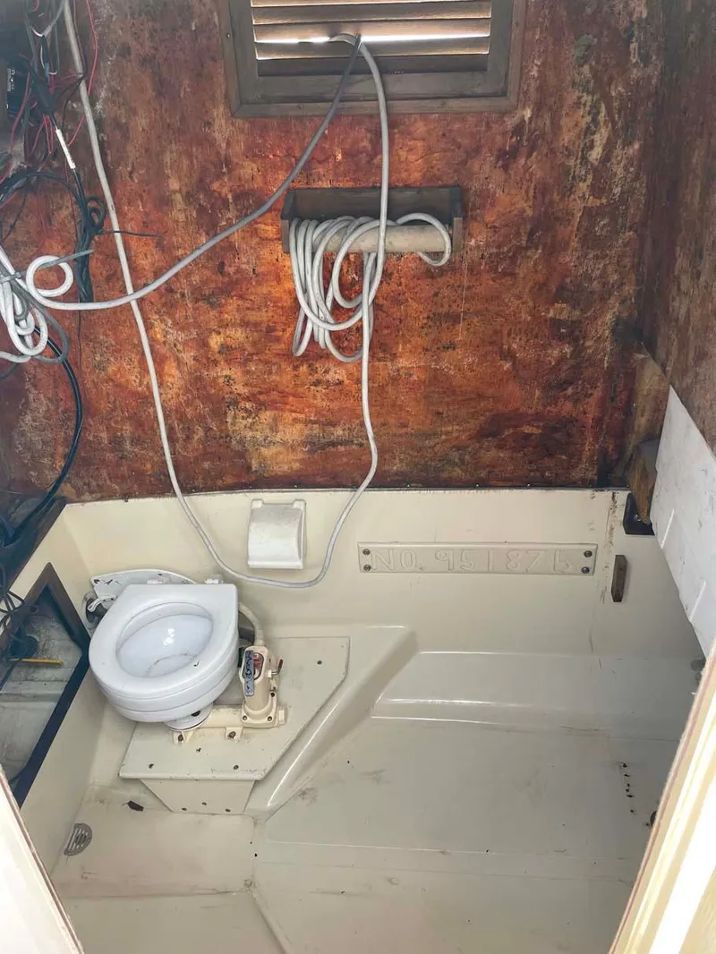 Slide: The Image of 1989 Rybo Runner Center Console boat interior with toilet and exposed wiring. - 17