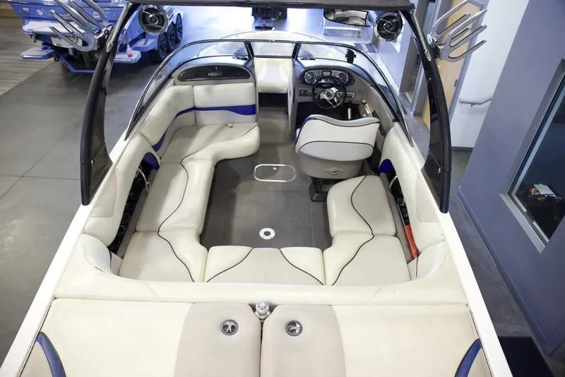 Slide: The Image of 2008 Malibu 21 VLX boat interior with white and blue seating, steering wheel, and spacious layout. - 10