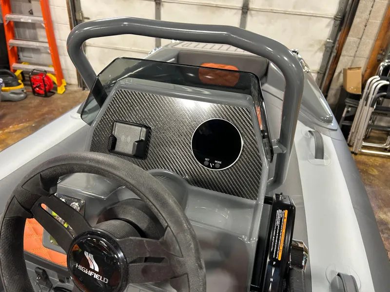 Slide: The Image of 2024 Highfield Sport 330 boat dashboard with steering wheel and carbon fiber panel. - 2
