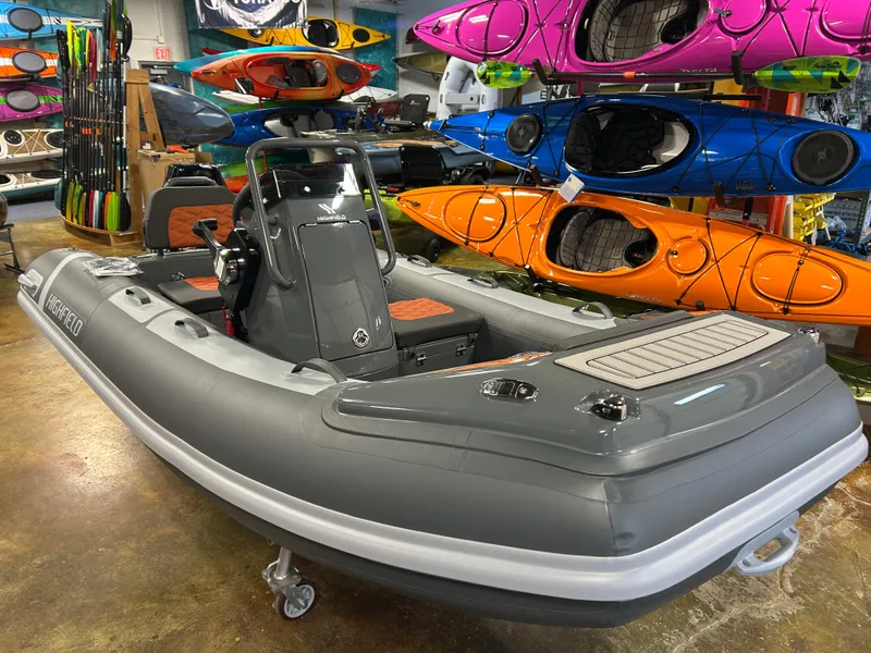 Slide: The Image of 2024 Highfield Sport 330 inflatable boat displayed in a showroom with colorful kayaks. - 6
