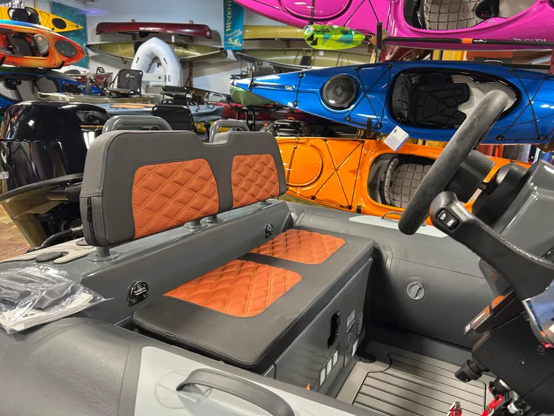 Slide: The Image of 2024 Highfield Sport 330 interior with orange quilted seats, surrounded by colorful kayaks. - 7