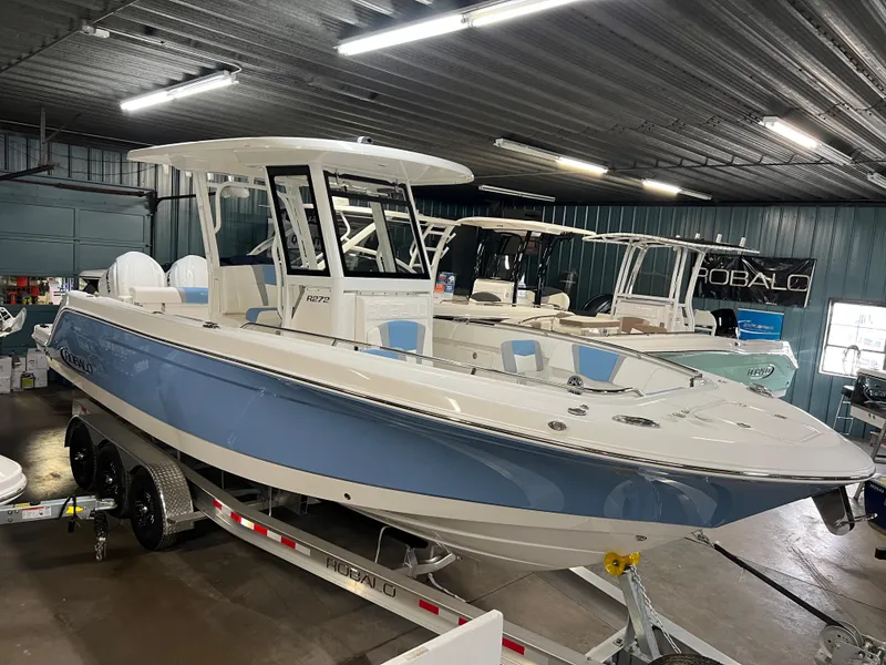 Slide: The Image of 2023 Robalo R 272 boat in showroom, blue and white design on trailer. - 14