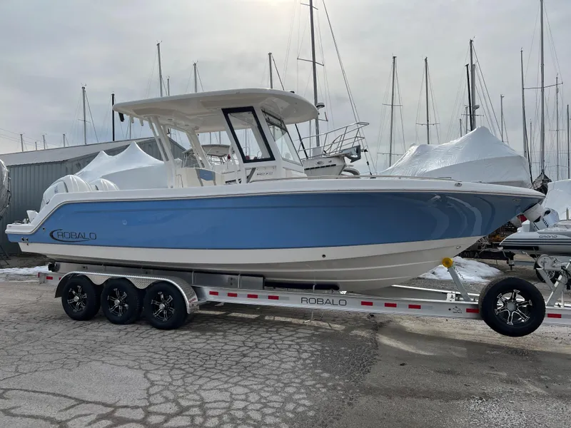 Slide: The Image of 2023 Robalo R 272 boat on trailer, blue hull, parked in marina. - 15