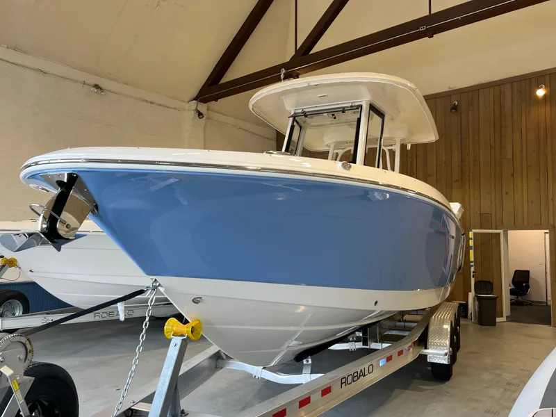 Slide: The Image of 2023 Robalo R 272 boat in showroom, blue hull, on trailer. - 2