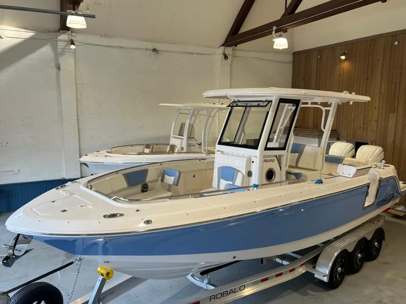 Slide: The Image of 2023 Robalo R 272 boat in showroom, blue and white design on trailer. - 3