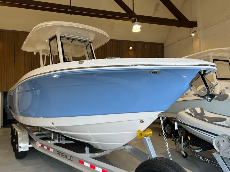 Slide: The Image of 2023 Robalo R 272 boat in showroom, blue and white hull on trailer. - 8