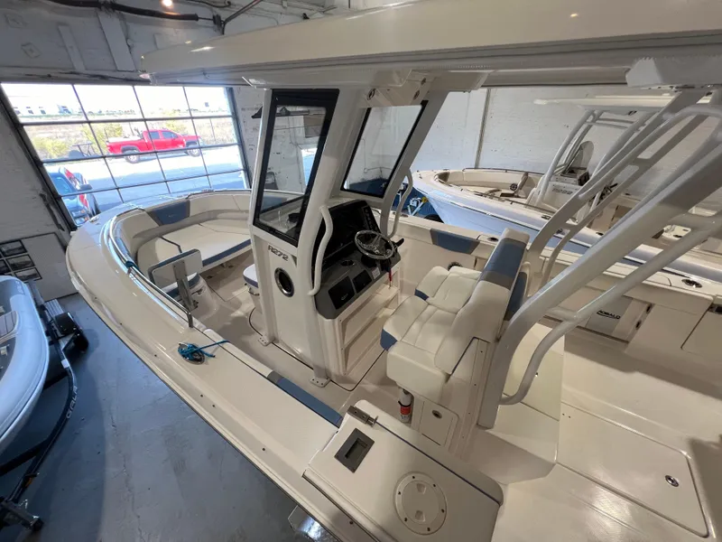 Slide: The Image of 2023 Robalo R 272 boat interior in showroom, featuring helm and seating area. - 9