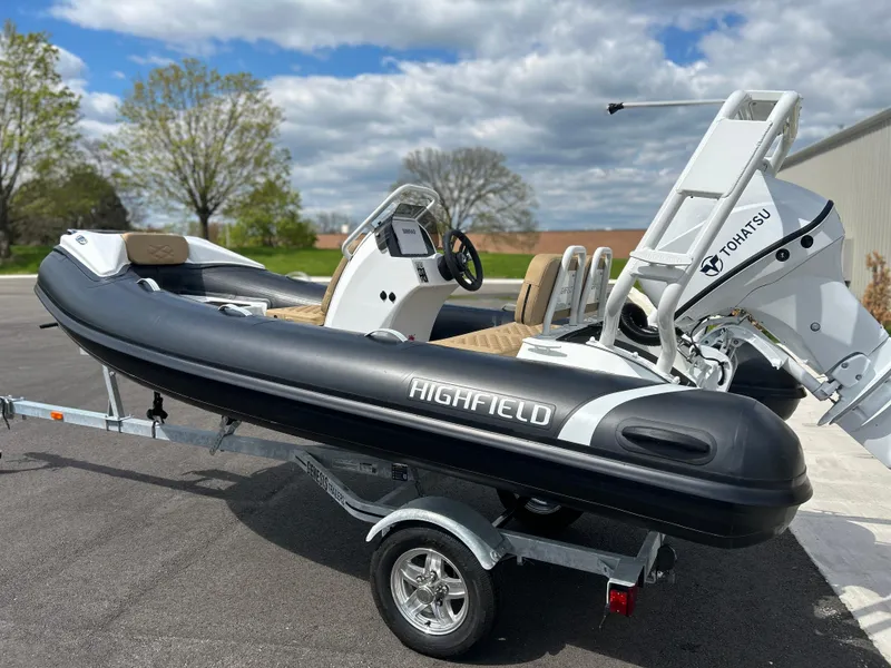 The Image of 2025 Highfield Sport 390 boat on trailer, featuring Tohatsu engine, parked outdoors. - 0