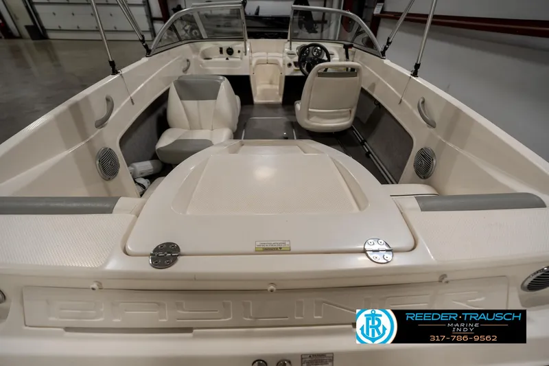 Slide: The Image of 2013 Bayliner 175 boat interior with seating and dashboard, showcased in a showroom. - 15