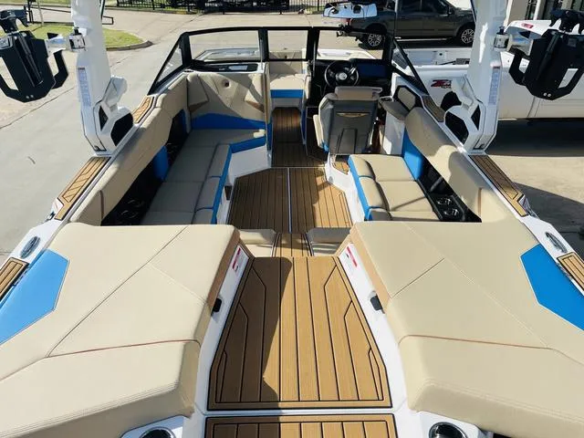 Slide: The Image of 2024 Nautique S23 boat interior with beige and blue seating, wood-style flooring. - 10
