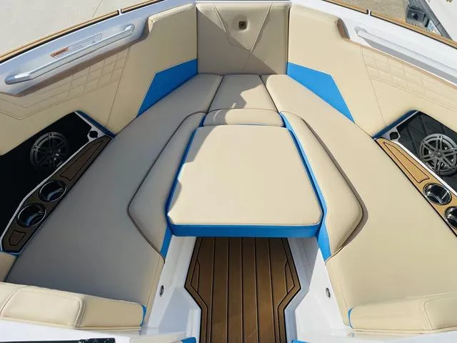 Slide: The Image of 2024 Nautique S23 boat interior with beige and blue seating, wood accents, and cup holders. - 12