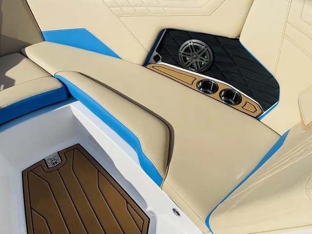 Slide: The Image of 2024 Nautique S23 interior with beige and blue seating, cup holders, and speaker. - 17