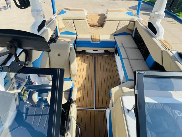 Slide: The Image of 2024 Nautique S23 boat interior with beige and blue seating, wood accents, and modern design. - 22
