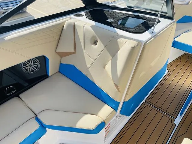 Slide: The Image of 2024 Nautique S23 boat interior with beige and blue seating, featuring modern design and wood flooring. - 26