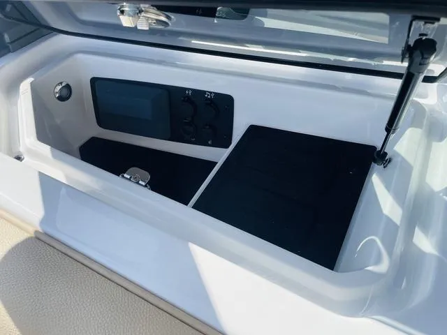 Slide: The Image of 2024 Nautique S23 storage compartment with control panel and sleek design. - 28