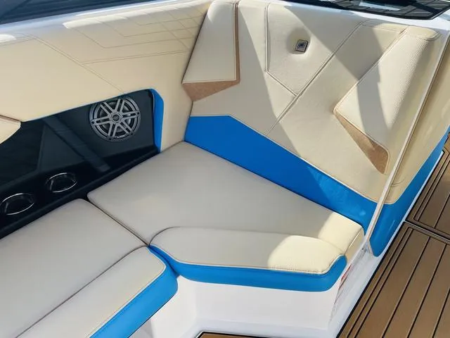Slide: The Image of 2024 Nautique S23 boat interior with beige and blue seating, speaker, and cup holders. - 30