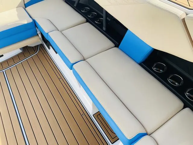 Slide: The Image of 2024 Nautique S23 boat interior with beige and blue seating, teak flooring. - 32