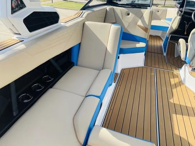 Slide: The Image of 2024 Nautique S23 boat interior with beige and blue seating, teak flooring. - 33