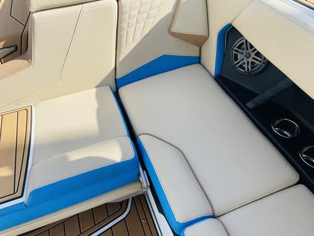 Slide: The Image of 2024 Nautique S23 boat interior with beige and blue seating, speaker, and cup holders. - 36