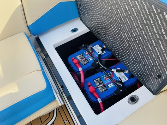 Slide: The Image of 2024 Nautique S23 boat battery compartment with dual blue batteries and red cables. - 37
