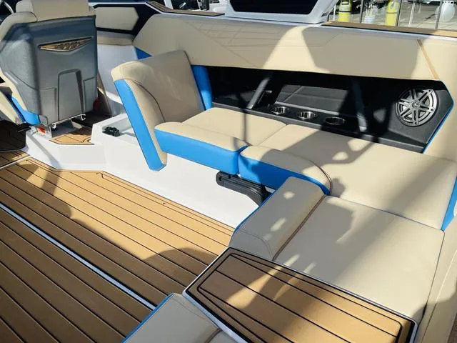 Slide: The Image of 2024 Nautique S23 interior with beige and blue seating, teak flooring, and cup holders. - 39