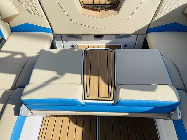 Slide: The Image of 2024 Nautique S23 boat interior with beige and blue seating, wood accents. - 45