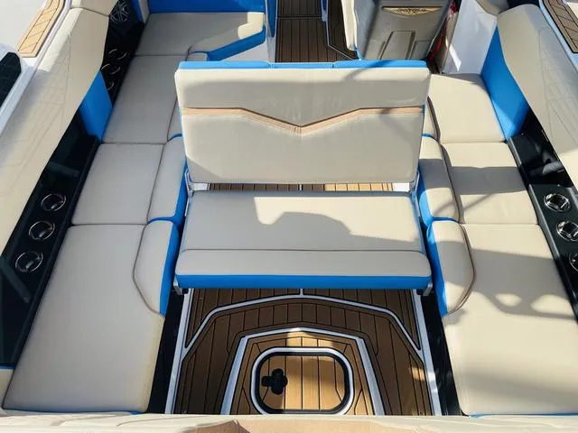 Slide: The Image of 2024 Nautique S23 boat interior with beige and blue seating, teak flooring. - 46