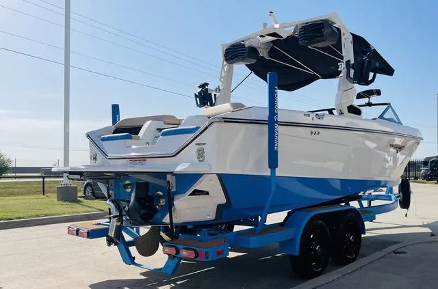 Slide: The Image of 2024 Nautique S23 boat on trailer, blue and white design, parked outdoors. - 6