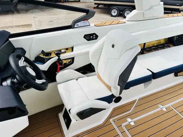 Slide: The Image of 2025 Nautique SUPER AIR G G25 boat interior with white seating and modern dashboard. - 20