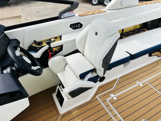 Slide: The Image of 2025 Nautique SUPER AIR G G25 boat interior with white seating and modern dashboard. - 21