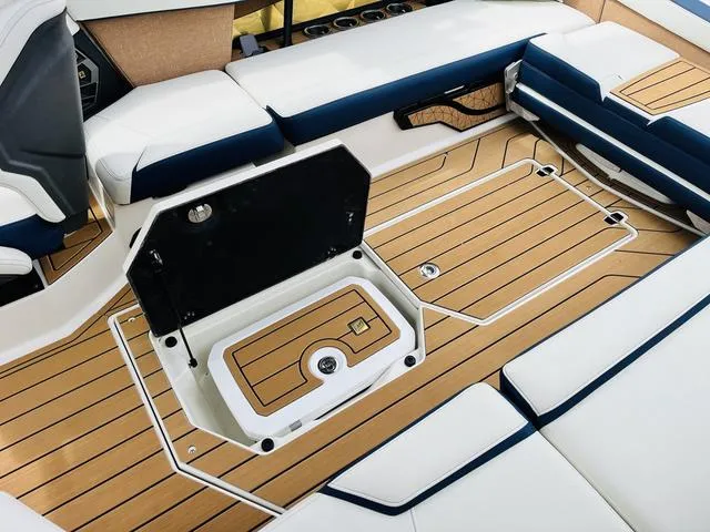Slide: The Image of 2025 Nautique SUPER AIR G G25 boat interior with open storage compartment and cushioned seating. - 26