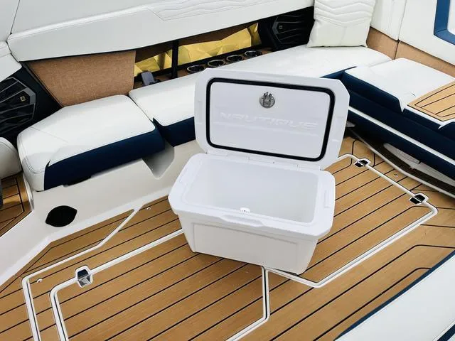 Slide: The Image of 2025 Nautique SUPER AIR G G25 boat interior with open cooler on teak deck. - 28