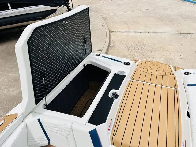 Slide: The Image of 2025 Nautique SUPER AIR G G25 boat with open storage compartment and teak deck. - 32