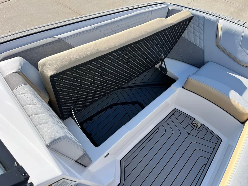 Slide: The Image of 2024 Nautique G25 boat interior with open storage compartment and cushioned seating. - 17