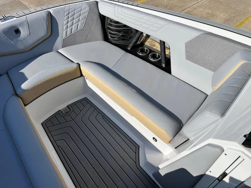 Slide: The Image of 2024 Nautique G25 boat interior with gray and beige seating, cup holders, and quilted accents. - 18