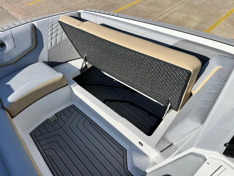 Slide: The Image of 2024 Nautique G25 boat interior with open storage compartment and cushioned seating. - 19