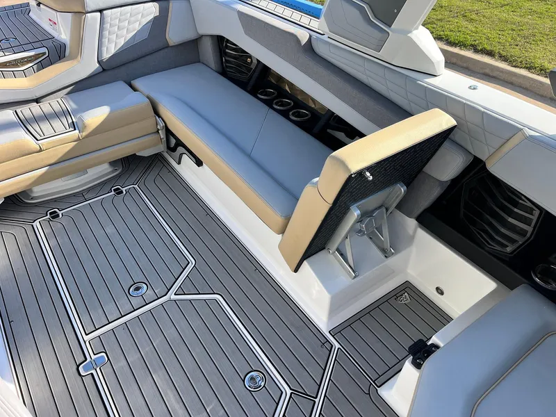Slide: The Image of 2024 Nautique G25 boat interior with gray and beige seating, cup holders, and sleek flooring. - 38