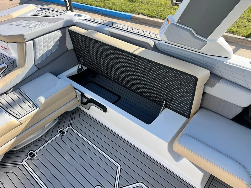 Slide: The Image of 2024 Nautique G25 boat interior with open storage compartment and cushioned seating. - 39