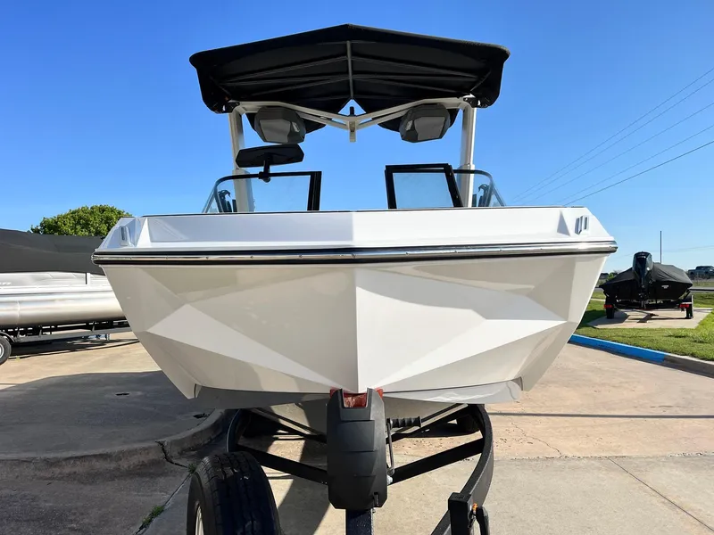 Slide: The Image of 2024 Nautique G25 boat on trailer, front view, under clear blue sky. - 4