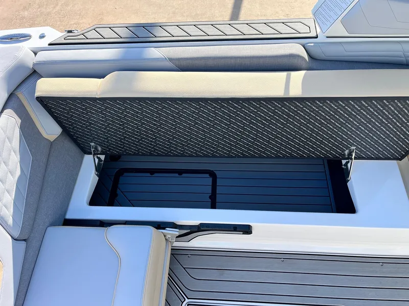 Slide: The Image of 2024 Nautique G25 boat interior storage compartment with open seat and sleek design. - 40