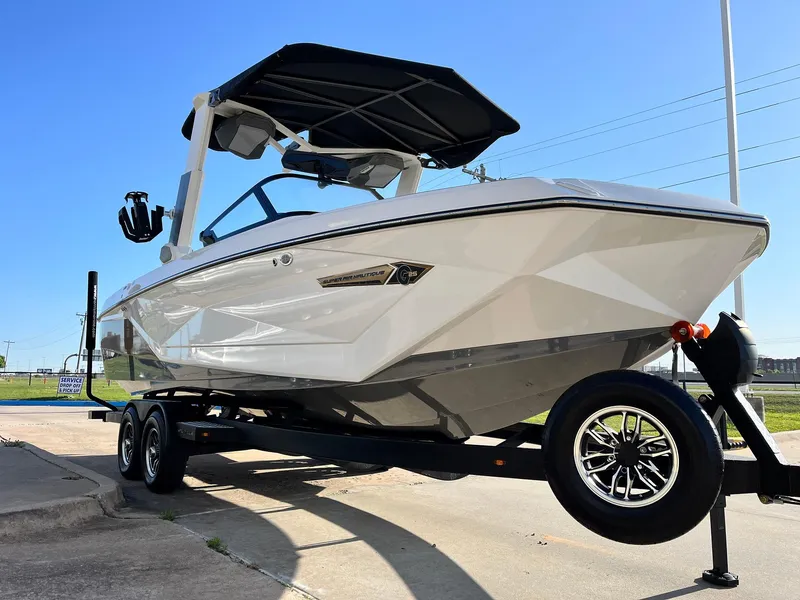 Slide: The Image of 2024 Nautique G25 boat on trailer, sleek design, white exterior, black canopy, sunny day. - 5