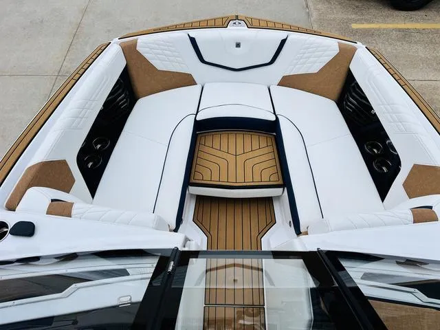 Slide: The Image of 2024 Nautique G23 boat interior with white and tan seating and wood accents. - 13