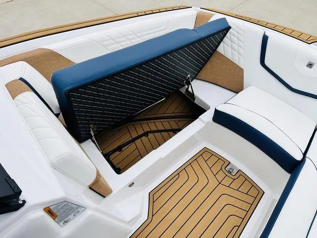 Slide: The Image of 2024 Nautique G23 boat interior with open storage compartment, featuring white and blue seating. - 15