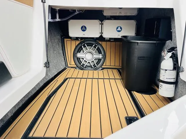 Slide: The Image of 2024 Nautique G23 interior storage with speaker, fire extinguisher, and wooden flooring. - 27
